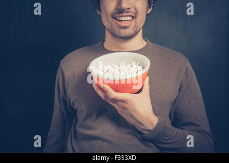 Ein lächelnder junge Mann hält eine Schüssel Popcorn Stockfoto