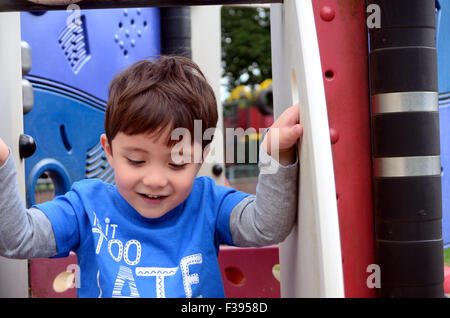 Ein kleiner Junge spielt auf einem Klettergerüst im Park. Stockfoto