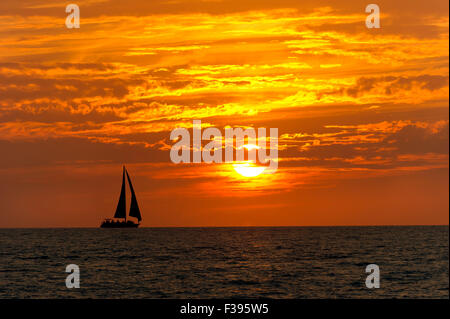 Segelboot Sunset ist eine bunte, lebendige orange und gelb Wolkengebilde Sonnenuntergang. Stockfoto