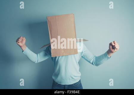 Ein Mann mit einem Karton auf dem Kopf ist begeistert und hebt seine Arme Stockfoto