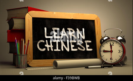 Lernen Sie Chinesisch - Tafel mit handgezeichneten Text, Stapel von Büchern, Wecker und Papierrollen auf der Hintergrund jedoch unscharf. Motivatio Stockfoto