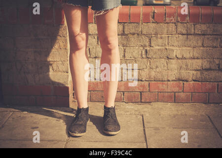 Closeup auf eine junge Frau Beine wie sie an einem sonnigen Tag auf der Straße steht Stockfoto