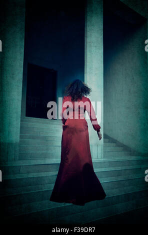 Frau im roten Abendkleid, die Treppe hinauf läuft Stockfoto