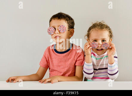 Jungen und Mädchen mit Sonnenbrille von Cookies gemacht mit Streuseln bedeckt Stockfoto