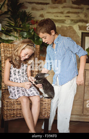 Jungen und Mädchen spielen mit ihrem Haustier Kaninchen Stockfoto