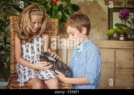 Jungen und Mädchen spielen mit ihrem Haustier Kaninchen Stockfoto