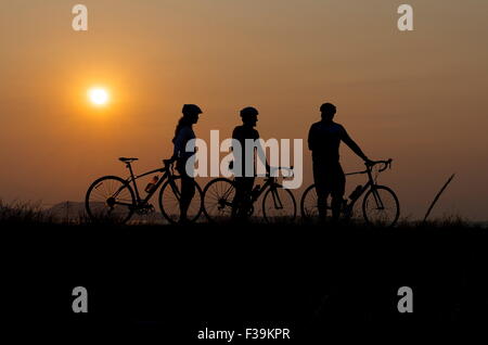 Silhouette der drei Radfahrer bei Sonnenuntergang Stockfoto