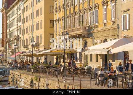 Triest Italien Uferpromenade, Blick auf die Via Gioacchino Rossini bei Sonnenuntergang, während die Leute vor Cafés und Bars sitzen und den Canal Grande in Triest überblicken Stockfoto