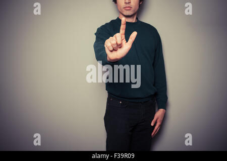 Ein junger Mann ist zeigen oder per Knopfdruck mit dem finger Stockfoto