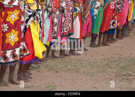 Eine Reihe barfuß-Maasai-Frauen, die die traditionellen Schalen namens Kangas tragen, in einem Dorf in der Nähe der Masai Mara, Ostafrika Stockfoto