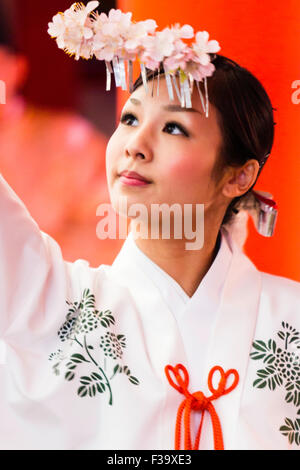 Japan, Ikuta Schrein, Kobe. Miko, shrine Maiden, Vollführung ritueller Tanz namens Kagura, mit Zweig sakaki zu Ihrem Kopf im Neuen Jahr beigefügt. Stockfoto