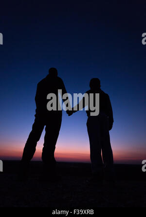 Förderung und Erziehung Konzept Foto von Vater und Sohn in der Silhouette, die Hand in Hand, den Sonnenuntergang beobachten Stockfoto