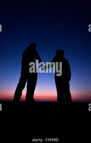 Förderung und Erziehung Konzept Foto von Vater und Sohn in der Silhouette, die Hand in Hand, den Sonnenuntergang beobachten Stockfoto