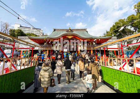 Ikuta Schrein, Kobe, Japan während New Year Festival. Tagsüber, Menschen zu Fuß zwischen zwei Reihen von omikuji Zähler auf die wichtigsten vermilion Schrein. Stockfoto