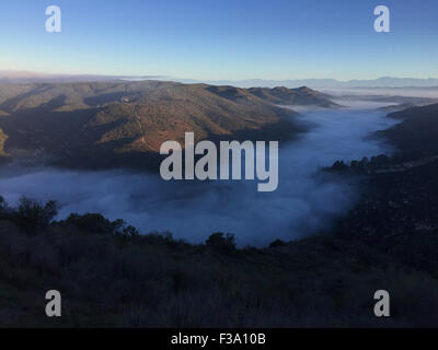 Laguna Beach, Kalifornien, USA. 27. Sep, 2015. Ein Blick vom "Top Of The World" der Nebel gefüllt Laguna Canyon 133 hwy bei Sonnenaufgang in Aliso Woods Canyon. Aliso Holz Canyon und Laguna Coast Wilderness Park liegen einige der letzten verbliebenen Küsten Schluchten in Südkalifornien. Felsige Klippen ragen über den Canyon Trails. Die Küsten Salbei Scrub-Gemeinschaft umfasst Kuppen und Hänge, zusammen mit Patches Native Tal Grasland und Maritime Chaparral. Laguna Coast Wilderness Park ist Teil des Programms natürliche Gemeinschaft Naturschutzplanung, das seltene und gefährdete Spec schützen soll Stockfoto