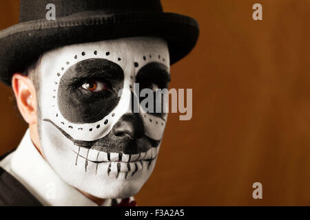 Porträt eines Mannes mit Calaveras Make-up, mit Melone, einem braunen Hintergrund Stockfoto