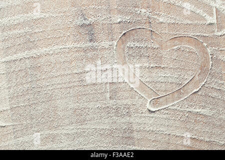 Herz aus Weißmehl auf Küchentisch Stockfoto