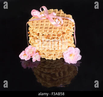 Runde Waffeln gebunden mit einer rosa Schleife auf schwarzem Hintergrund Stockfoto