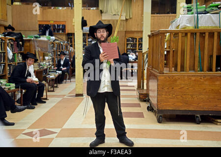 Eine religiöse jüdische jungen Mann mit einem Esrog und Lulaw am Morgen Sukkot Dienstleistungen auf eine Synagoge in Brooklyn, New York Stockfoto