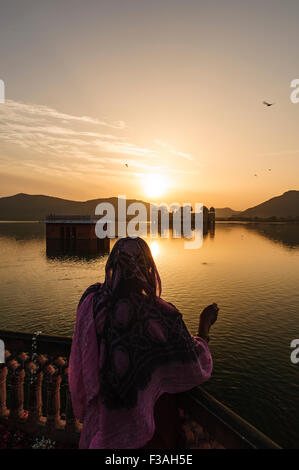 Eine Frau, die Fütterung einen Fisch im Jal Mahal Palast bei Sonnenaufgang. JAL Mahal (Wasserpalast) ist ein See im Laufe des 18. Jahrhunderts gebaut wurde. Stockfoto