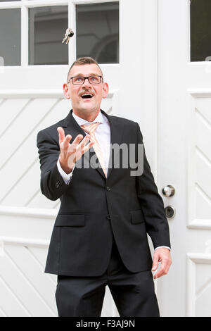 Geschäftsmann vor Tür werfen einen Schlüsselbund in der Luft Stockfoto