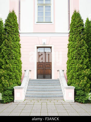 Treppe mit hohen grünen Bäume Randbemerkungen zu einem rosa Haus aus Stein mit einem dunklen braunen Holztür Stockfoto