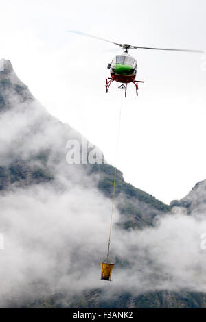 Falcade, Belluno, Italien - 21. August 2015: Transporthubschrauber liefert Material für eine Baustelle in den Bergen Stockfoto