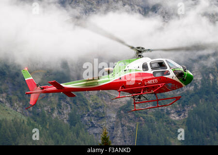 Falcade, Belluno, Italien - 21. August 2015: Transporthubschrauber liefert Material für eine Baustelle in den Bergen Stockfoto