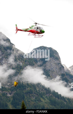 Falcade, Belluno, Italien - 21. August 2015: Transporthubschrauber liefert Material für eine Baustelle in den Bergen Stockfoto