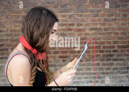 Hispanischen Mädchen mit einem Tablet mit roten Kopfhörer. Trendy und urbanen Stil. Stockfoto