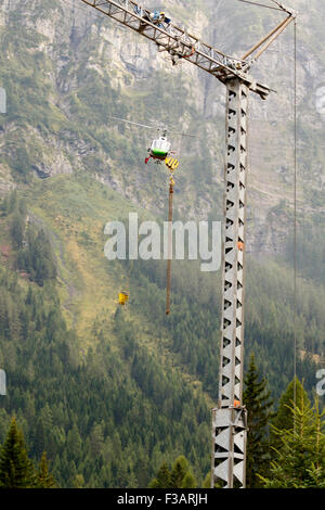 Falcade, Belluno, Italien - 21. August 2015: Transporthubschrauber liefert Material für eine Baustelle in den Bergen Stockfoto