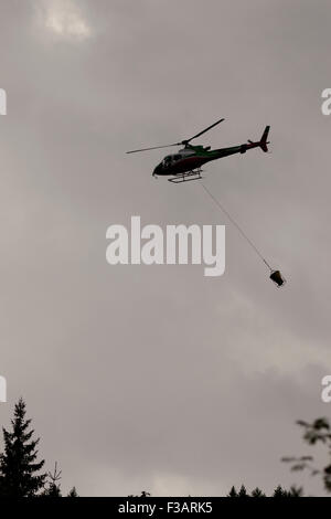 Falcade, Belluno, Italien - 21. August 2015: Transporthubschrauber liefert Material für eine Baustelle in den Bergen Stockfoto