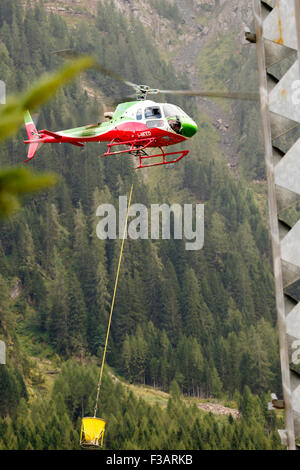 Falcade, Belluno, Italien - 21. August 2015: Transporthubschrauber liefert Material für eine Baustelle in den Bergen Stockfoto