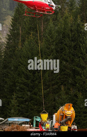 Falcade, Belluno, Italien - 21. August 2015: Transporthubschrauber liefert Material für eine Baustelle in den Bergen Stockfoto