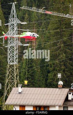 Falcade, Belluno, Italien - 21. August 2015: Transporthubschrauber liefert Material für eine Baustelle in den Bergen Stockfoto