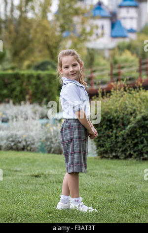 Kleines Mädchen mit Schuluniform in grünen Park. Zurück zur Schule. Stockfoto