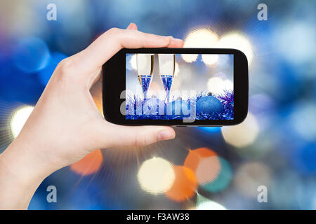 Mann nimmt Foto von Weihnachten Stillleben - zwei Gläser Champagner blau Weihnachten Dekorationen mit Duffuse blau Weihnachten Leuchten b Stockfoto