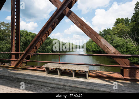 Sitzbank auf der wallkill River Rail Trail Bridge in den Catskills, New York mit Blick auf den Fluss durch die Brücke Struktur. Stockfoto