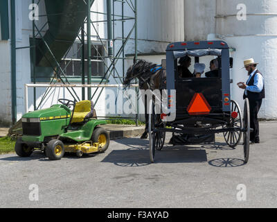 Amische Pferd und quadratischen Wagen parkte neben einem John Deere LX188 Fahrt auf Rasenmäher Stockfoto