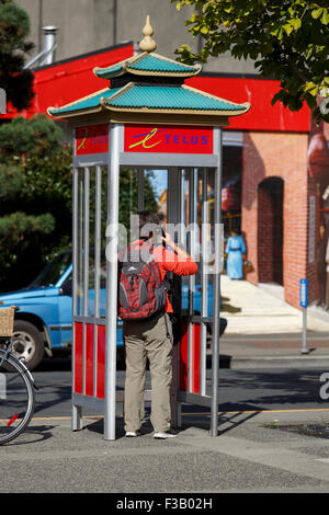 Person, die einen Anruf von einer Telefonzelle in Chinatown Victoria British Columbia Stockfoto