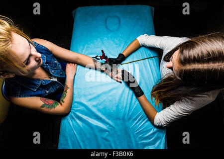 Tätowierer macht das Tattoo auf der Mädchen Seite Stockfoto