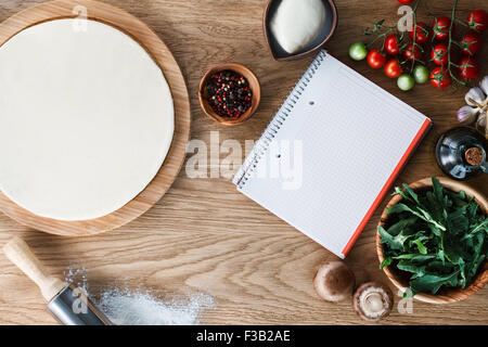 Copybook Teig Pizzateig und Zutaten auf einem Holztisch strukturierte umgeben. Ansicht von oben. Stockfoto