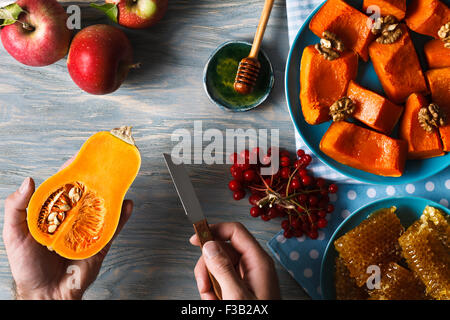 Herbst-Menü. Mannhände halten kleine Kürbis und ein Messer vor dem Hintergrund von frischen Äpfeln, eine Reihe von Viburnum Beeren, h Stockfoto