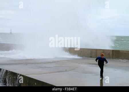 Chicago, Illinois, USA. 3. Oktober 2015.  Ein kleiner Junge weicht eine Welle auf der Ufermauer in Montrose Beach. Mehrere Tage starke Nordostwinde getrieben haben "Wellenlinien" bis zu 15 Fuß hoch auf Chicagos Ufer. Bildnachweis: Todd Bannor/Alamy Live-Nachrichten Stockfoto