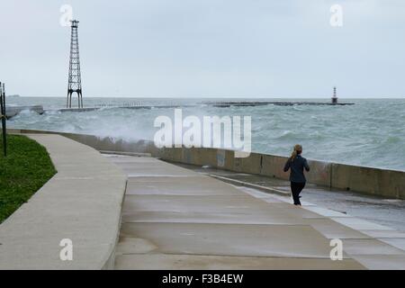 Chicago, Illinois, USA. 3. Oktober 2015.  Eine junge Frau weicht Wellen während der Einnahme von nassen Joggen entlang der Ufermauer am Montrose Strand heute. Mehrere Tage starke Nordostwinde haben die Wellen so hoch wie 15 Fuß auf Chicagos Ufer getrieben. Bildnachweis: Todd Bannor/Alamy Live-Nachrichten Stockfoto