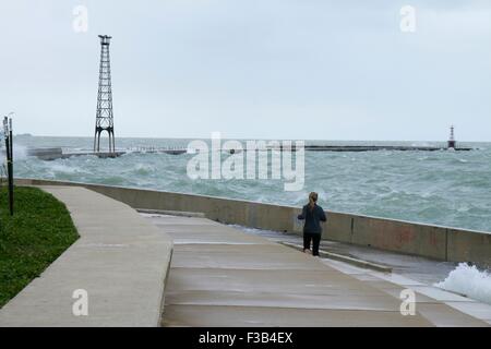 Chicago, Illinois, USA. 3. Oktober 2015.  Eine junge Frau weicht Wellen während der Einnahme von nassen Joggen entlang der Ufermauer am Montrose Strand heute. Mehrere Tage starke Nordostwinde haben die Wellen so hoch wie 15 Fuß auf Chicagos Ufer getrieben. Bildnachweis: Todd Bannor/Alamy Live-Nachrichten Stockfoto