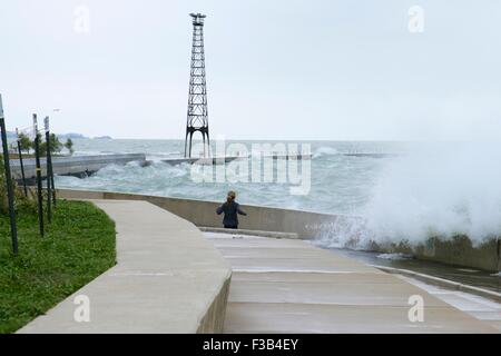 Chicago, Illinois, USA. 3. Oktober 2015.  Eine junge Frau weicht Wellen während der Einnahme von nassen Joggen entlang der Ufermauer am Montrose Strand heute. Mehrere Tage starke Nordostwinde haben die Wellen so hoch wie 15 Fuß auf Chicagos Ufer getrieben. Bildnachweis: Todd Bannor/Alamy Live-Nachrichten Stockfoto