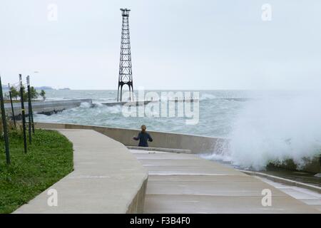 Chicago, Illinois, USA. 3. Oktober 2015.  Eine junge Frau weicht Wellen während der Einnahme von nassen Joggen entlang der Ufermauer am Montrose Strand heute. Mehrere Tage starke Nordostwinde haben die Wellen so hoch wie 15 Fuß auf Chicagos Ufer getrieben. Bildnachweis: Todd Bannor/Alamy Live-Nachrichten Stockfoto