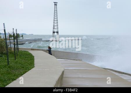 Chicago, Illinois, USA. 3. Oktober 2015.  Eine junge Frau weicht Wellen während der Einnahme von nassen Joggen entlang der Ufermauer am Montrose Strand heute. Mehrere Tage starke Nordostwinde haben die Wellen so hoch wie 15 Fuß auf Chicagos Ufer getrieben. Bildnachweis: Todd Bannor/Alamy Live-Nachrichten Stockfoto