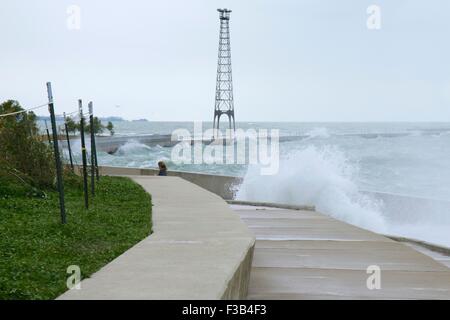 Chicago, Illinois, USA. 3. Oktober 2015.  Eine junge Frau weicht Wellen während der Einnahme von nassen Joggen entlang der Ufermauer am Montrose Strand heute. Mehrere Tage starke Nordostwinde haben die Wellen so hoch wie 15 Fuß auf Chicagos Ufer getrieben. Bildnachweis: Todd Bannor/Alamy Live-Nachrichten Stockfoto